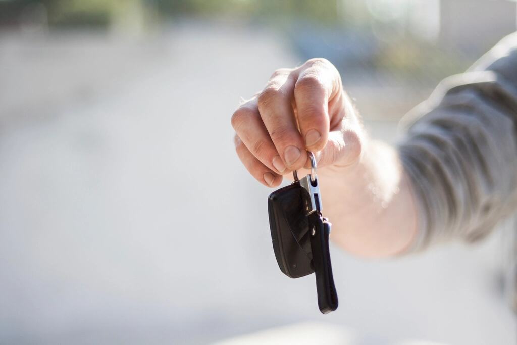 Een hand houdt een autosleutel vast, klaar om over te geven.