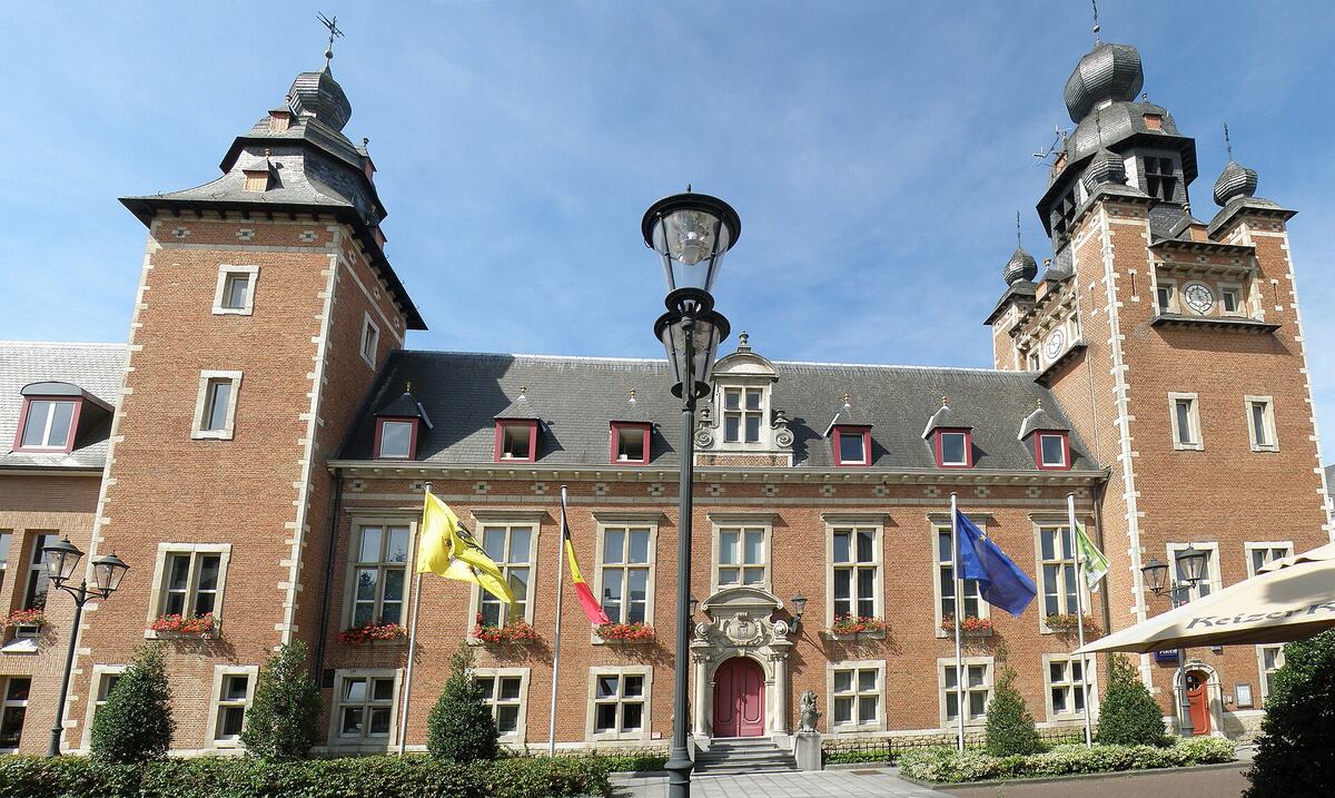 Het gemeentehuis van Duffel, een bakstenen kasteelgebouw met torens en vlaggen.